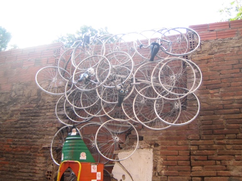 Escultura de llantas sobre pared del Taller de Bicis